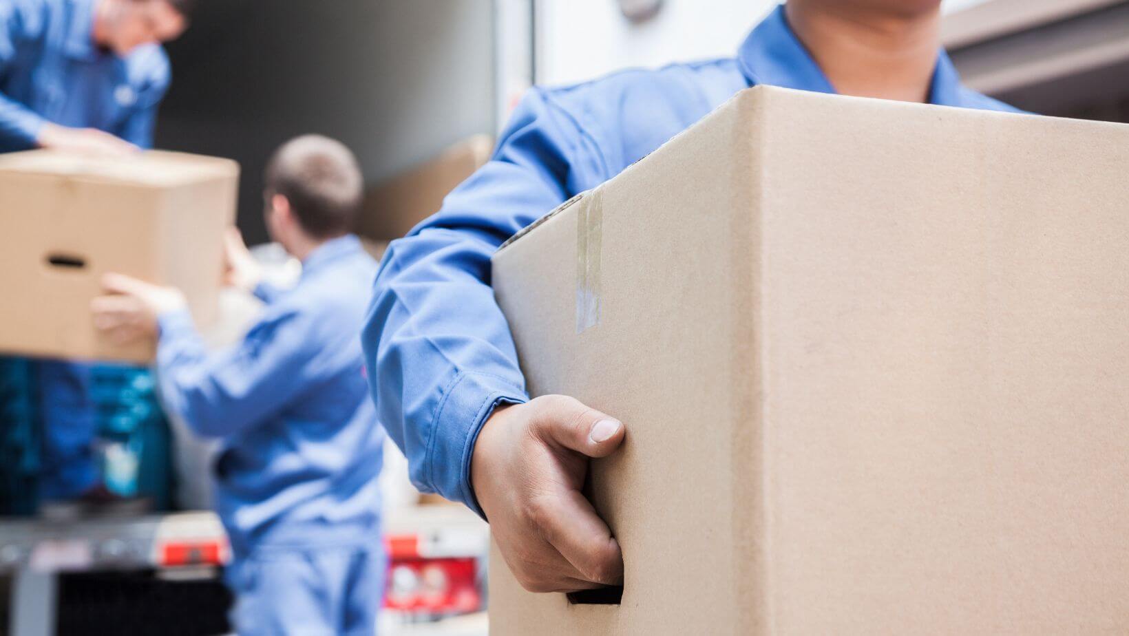 Professional movers transporting furniture and boxes in a residential area.